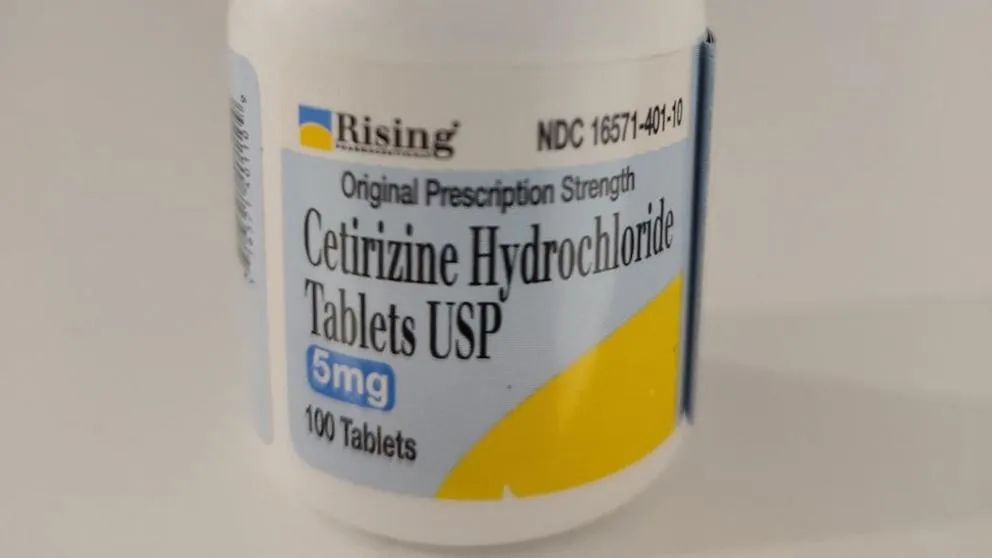 White bottle of Cetirizine Hydrochloride Tablets USP 5 mg with loose tablets in front