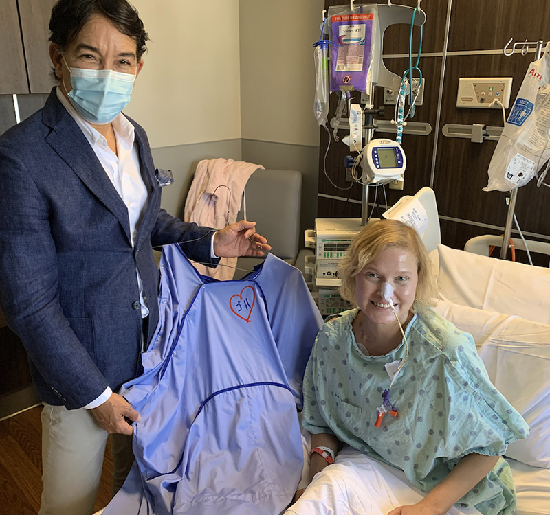 A René Ruiz designer patient gown in patterned blue fabric with front snaps, line access openings, and telemetry pockets