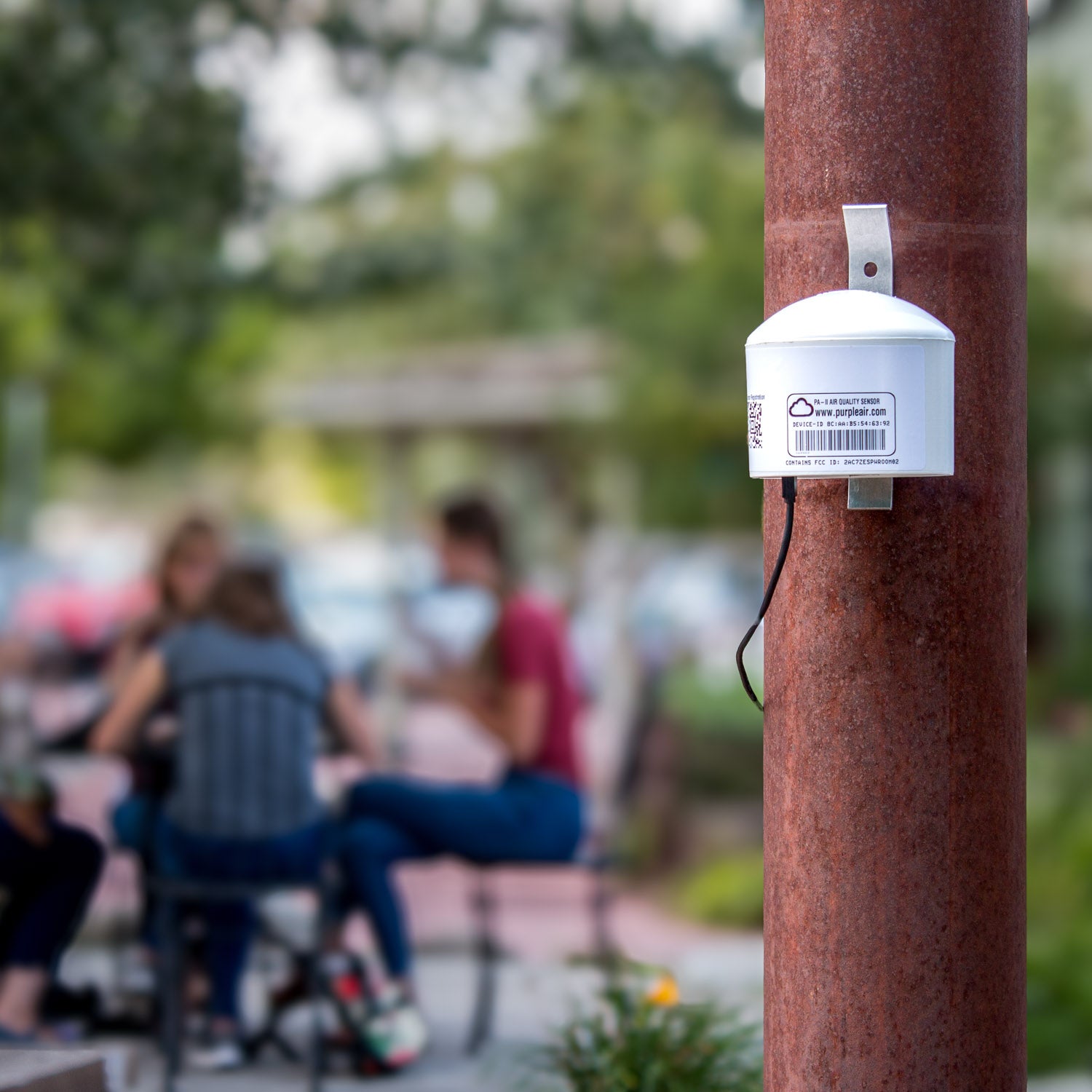 PurpleAir Classic outdoor PM2.5 air quality monitor mounted on a porch railing